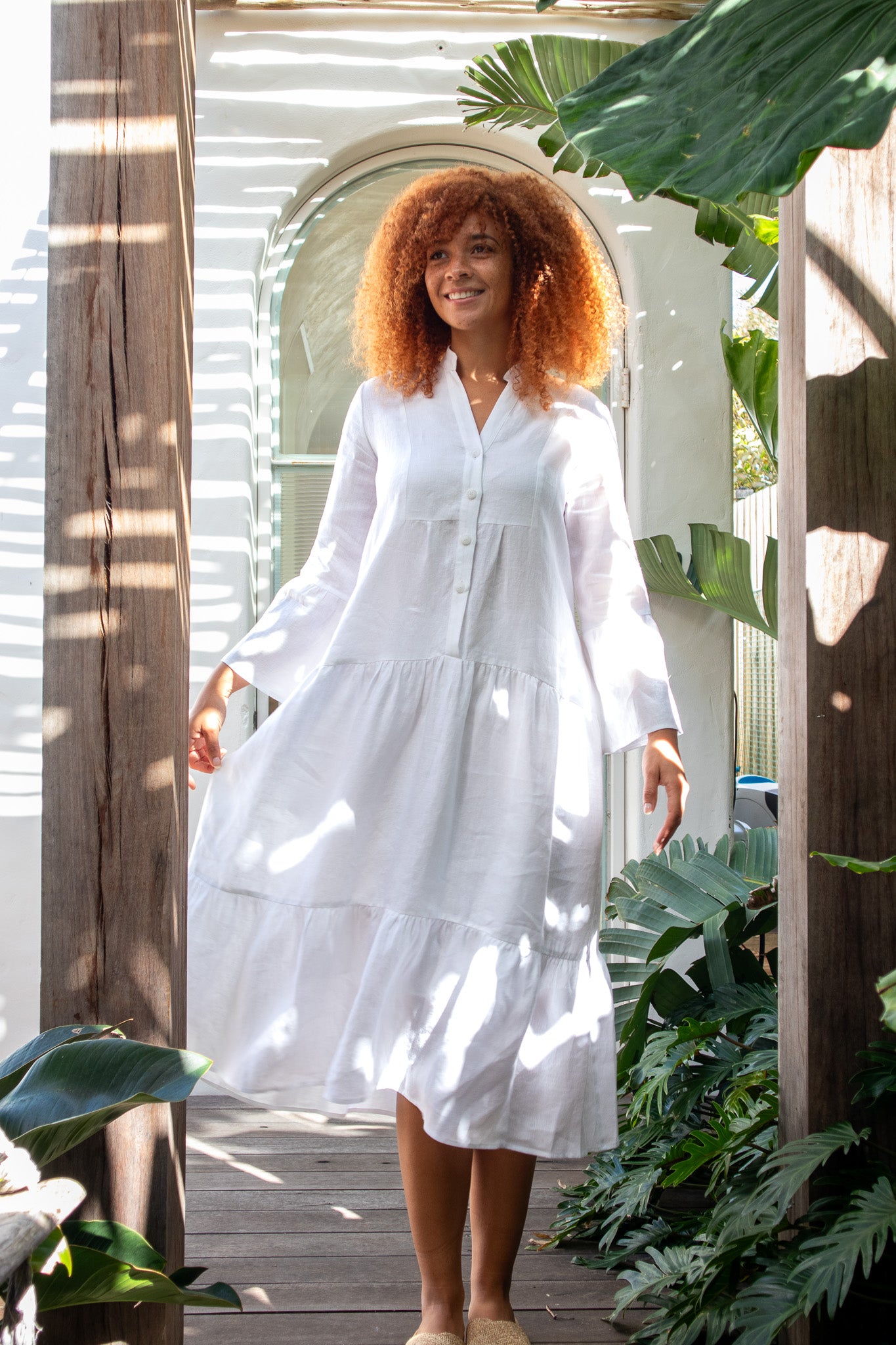 White linen dress worn by beautiful curly haired model 