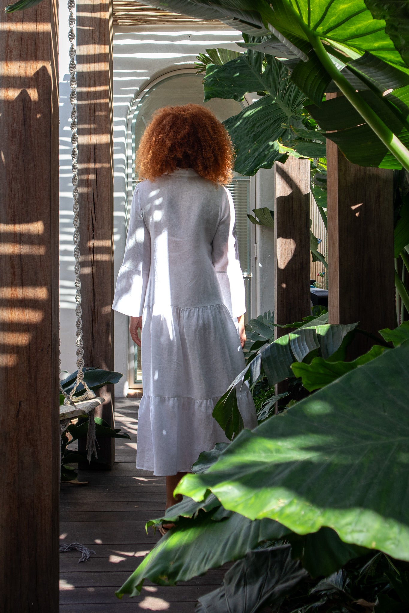 Model not facing the camera, showing the back of a white linen dress 