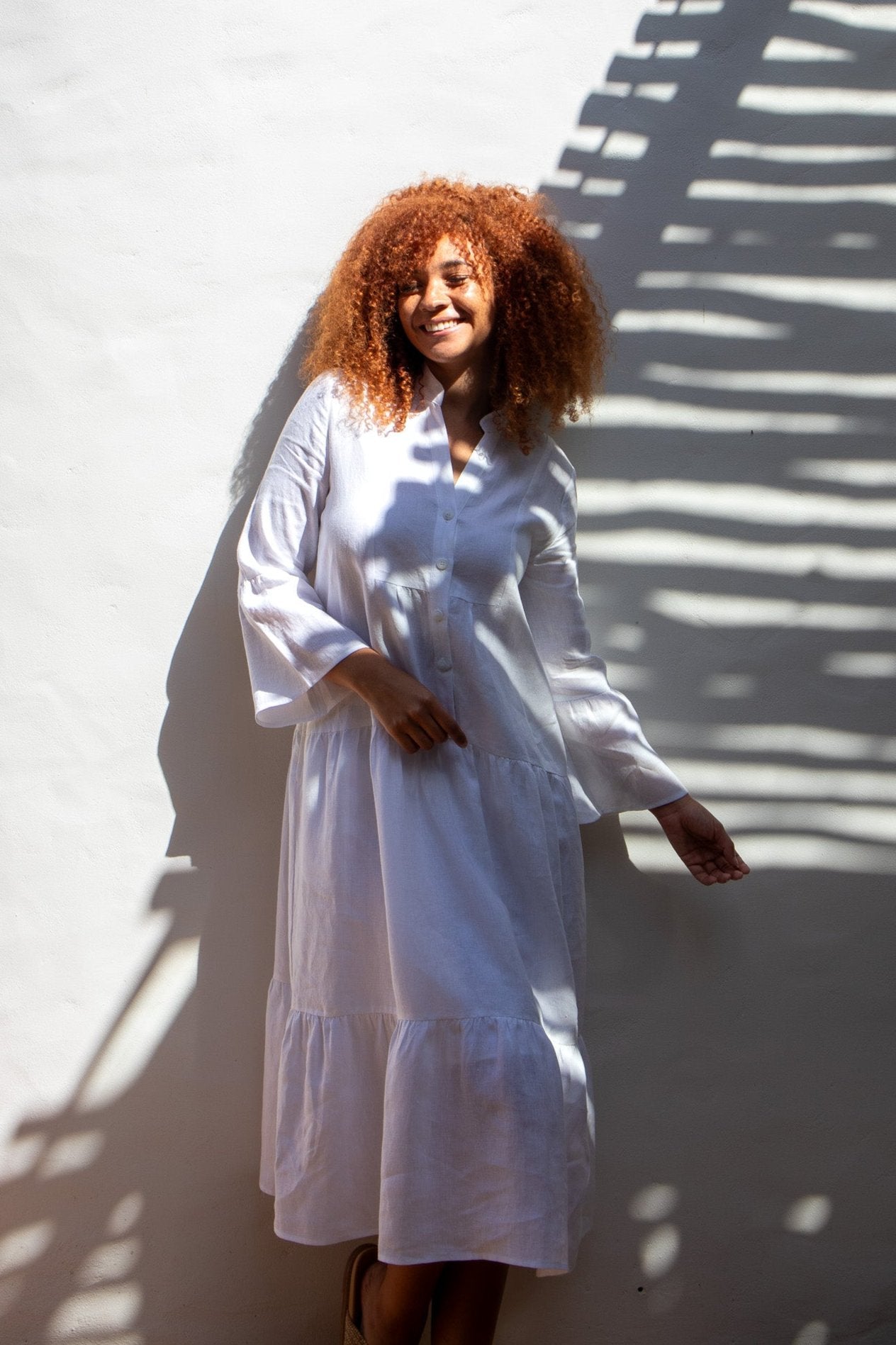 Model in white linen dress dancing showing the movement of the dress