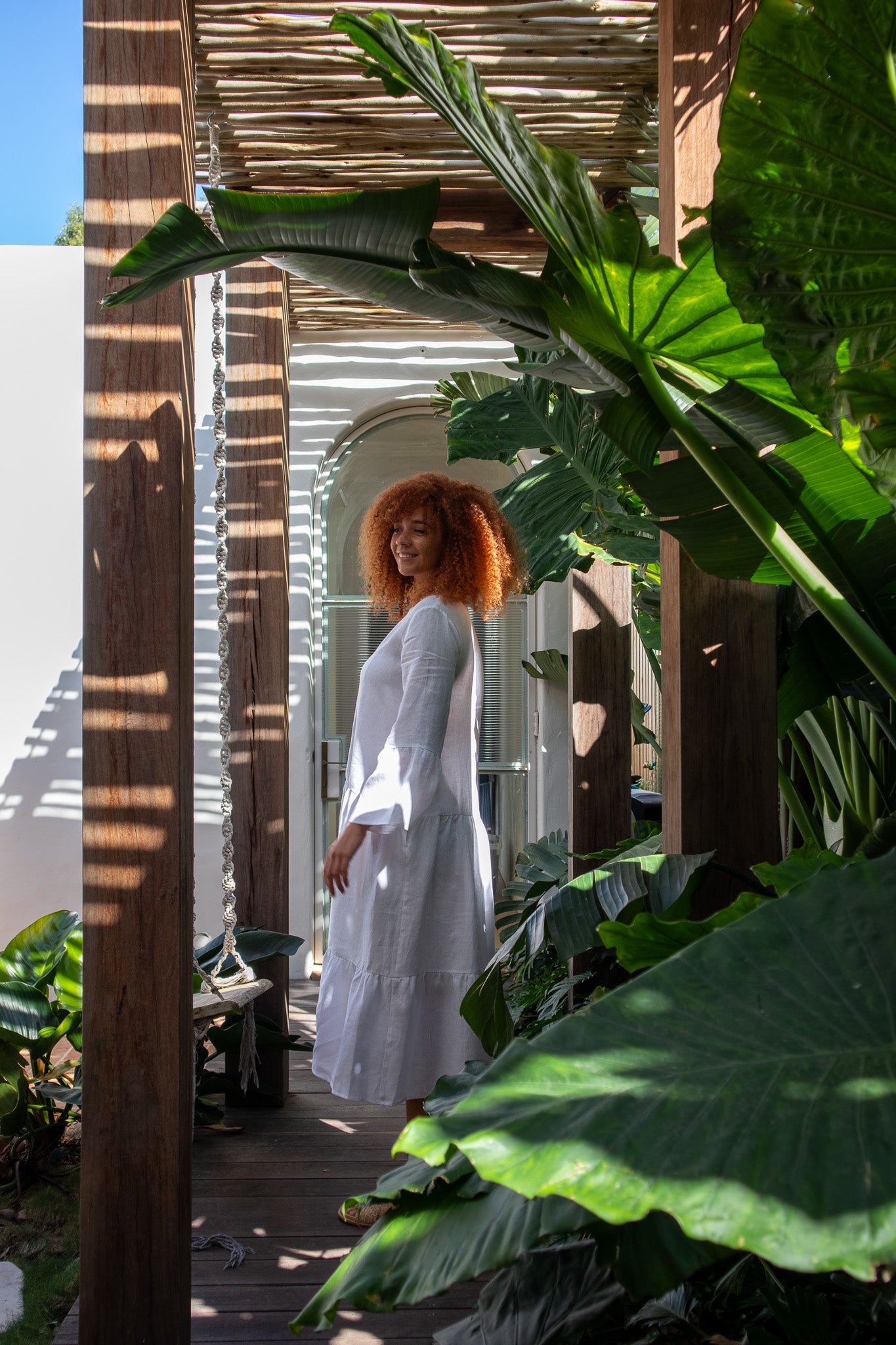 model wearing white linen dress facing to the side to show the detail 