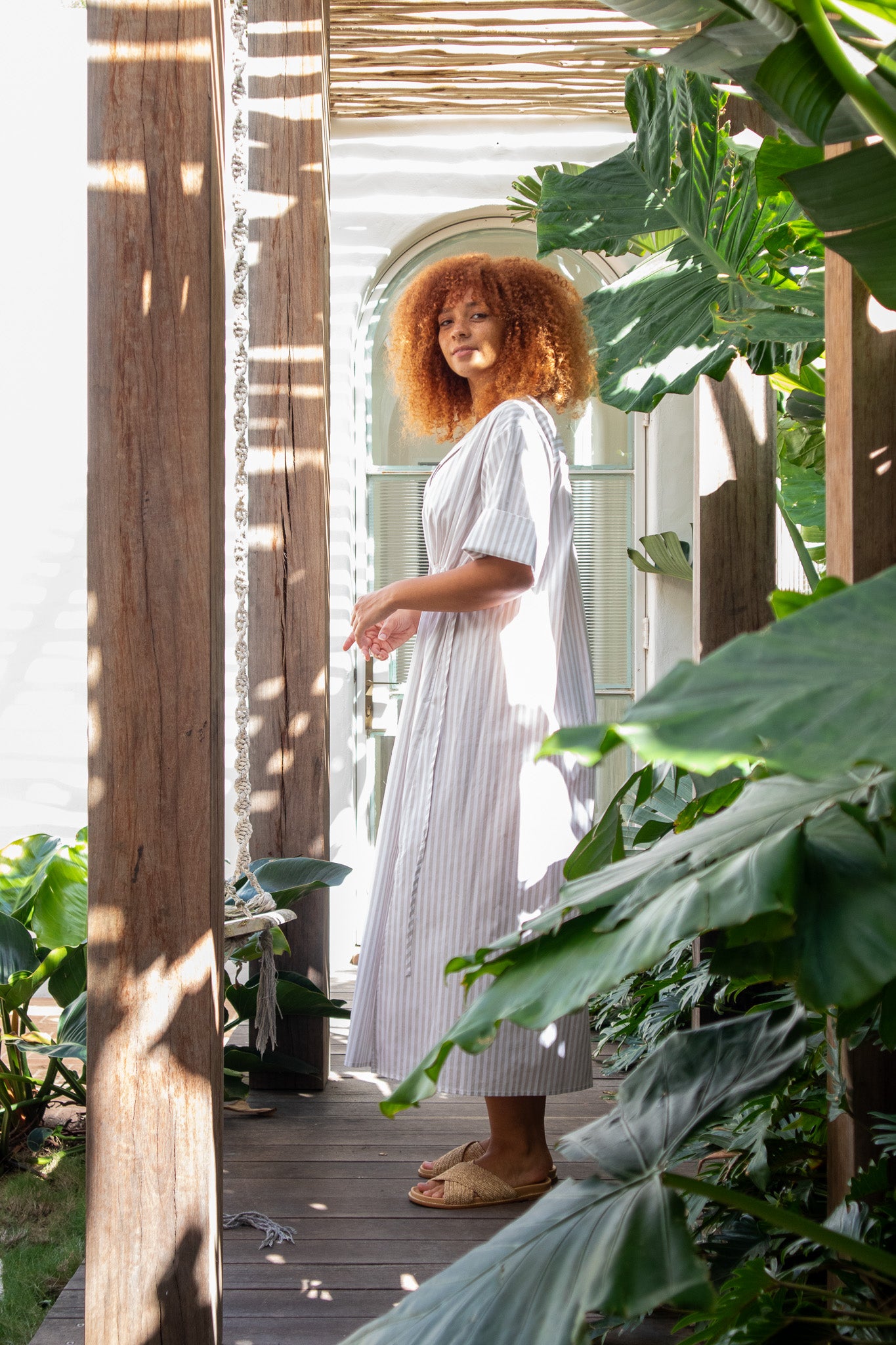 Model looking at the camera wearing a beige stripe cotton poplin dress from The boy and I 